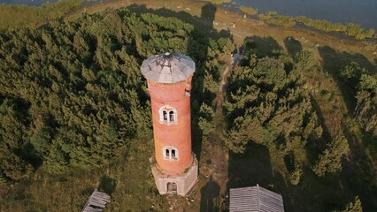 Fast aerial drone flight towards and over lost place lighthouse with zoom in at the coast of baltic sea - Estonia in Europe - nature helicopter flyover establishing shot summer 2022 - bird view