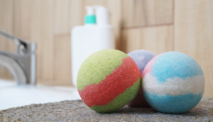 Colorful bath bombs on wicker mat in bathroom, closeup. Space for text