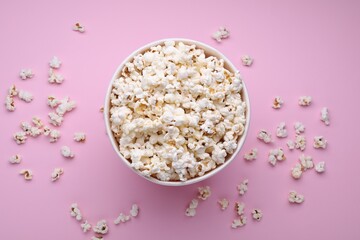 Bucket of tasty popcorn on pink background, flat lay