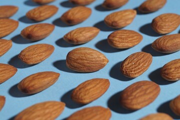 Delicious raw almonds on light blue background, closeup