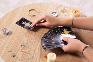 Soothsayer predicting future with tarot cards at table indoors, closeup