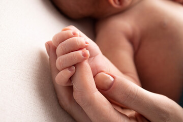 Close-up little hand of child and palm of mother and father. The newborn baby has a firm grip on the parent's finger after birth. A newborn holds on to mom's, dad's finger. 