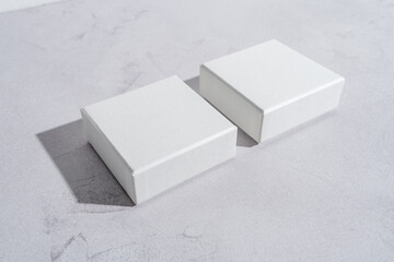 Two white square gift boxes mockup on gray concrete background. From above, top view, minimalist...