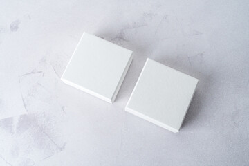 Two white square gift boxes mockup on gray concrete background. From above, top view, minimalist concept - 547572503
