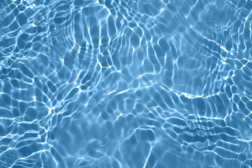 Defocus blurred transparent blue colored clear calm water surface texture with splashes and bubbles. Trendy abstract nature background. Water waves in sunlight with copy space. Blue watercolor shining
