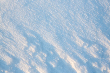 Beautiful winter background with snowy ground. Natural snow texture. Wind sculpted patterns on snow surface.