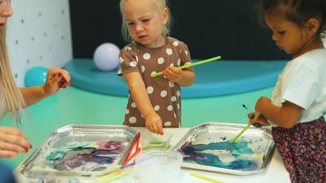 closeup view of cute preschoolers painting with sticks and paints, creative painting techniques for kids kindergarten. High quality 4k footage