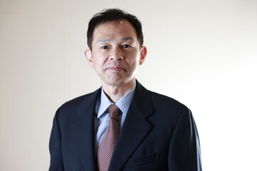 Middle-aged Japanese male businessman wearing navy blue suit on white background. Conceptual image of a project proposal, strategic business success and negotiation closing.