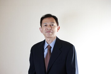 Middle-aged Japanese male businessman wearing navy blue suit on white background. Conceptual image of a project proposal, strategic business success and negotiation closing.