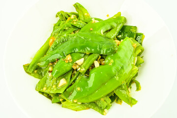 A plate of home cooked green peppers with garlic and tiger skin on a white background