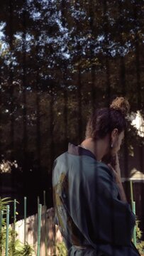 Man in a kimono smoking in his backyard 