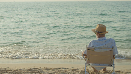 elderly men sit chair at the beach watching the sun and the sea on their summer vacation and they smile and enjoy their vacation.