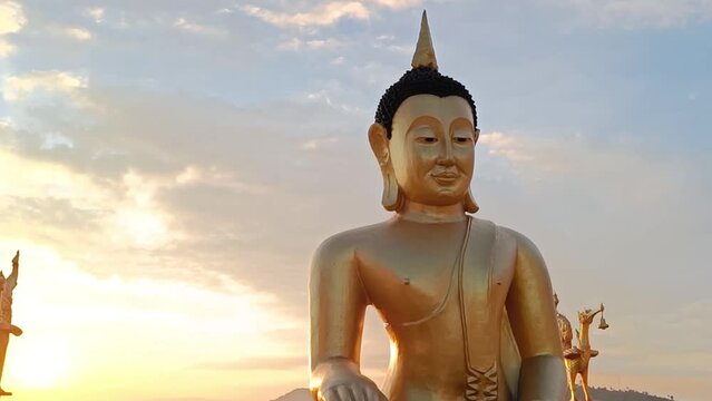 Golden Buddha statue against sunset sky in Thailand temple