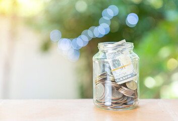 A clear glass jar filled with dollar bills and coins.