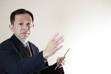 Middle-aged Japanese male businessman wearing navy blue suit on white background holding tablet PC. Conceptual image of a project proposal, strategic business success and negotiation closing.