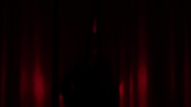 Elegant dancer, actress woman in enters the stage in a dark red background with circle light focusing on her