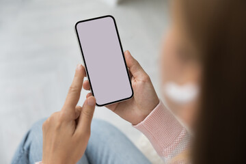 Unrecognizable woman holding smartphone with empty white mock up screen view, close up. Website surfing, lifestyle, modern tech, wireless device usage for communication, shopping or fun, mobile apps