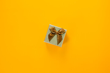 Mini golden gift box with ribbon on yellow background, giving special gift box for Merry New Year...