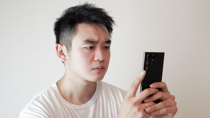Fototapeta premium an asian or caucasian man wearing plain white t shirt was typing on his phone isolated over a white background
