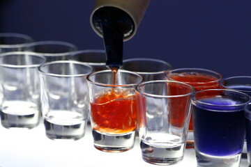 Colorful alcoholic drinks being poured in shot glasses