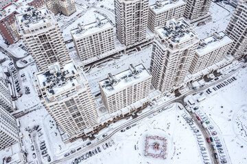 winter city scenery. snow-covered apartment buildings, rooftops, courtyards with parked cars. aerial overhead view.