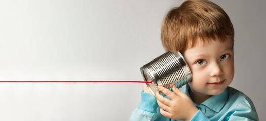 happy boy play in the tin can phone, boy attached a telephone to his ear - 547595557