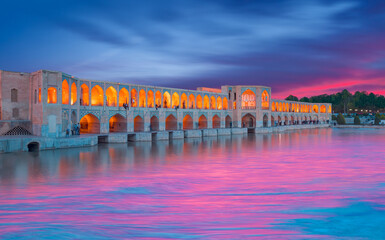 Menschen, die sich bei erstaunlichem Sonnenuntergang in der alten Khaju-Brücke ausruhen - Isfahan, Iran