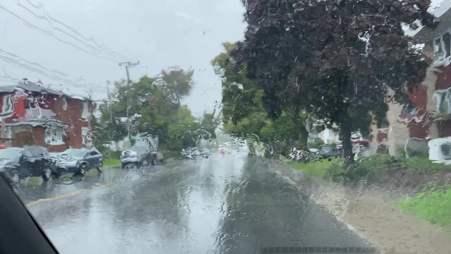 Une voiture est stationn&eacute;e sur le bord de la route. Il pleut. Les essuies-glaces ne fonctionnent pas. La vue de l'ext&eacute;rieur est brouill&eacute;e.