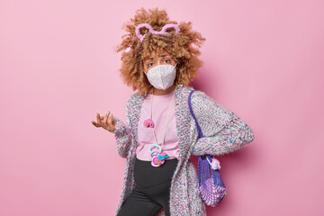 Indoor shot of confused hesitant pregnant woman wears protective facial mask to protect from viral influenza disease or coronavirus fights against pandemic prepares for childbirth. Expectant mother