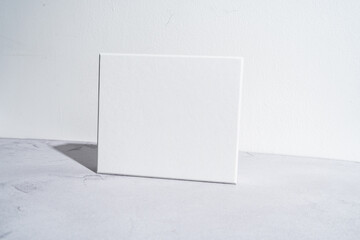 White square gift box mockup on gray concrete background. Closeup, shadows, minimalist concept