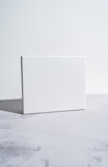 White square gift box mockup on gray concrete background. Closeup, shadows, minimalist concept