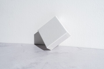 One small white square gift box mockup on gray concrete background. Closeup, shadows, minimalist concept - 547599142