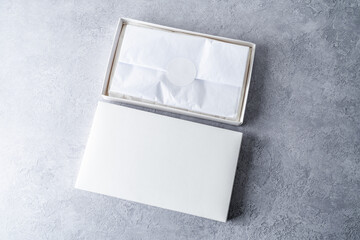 White square gift boxes with tissue wraping paper and round label, mockup on gray concrete background. From above, top view, minimalist concept - 547599349