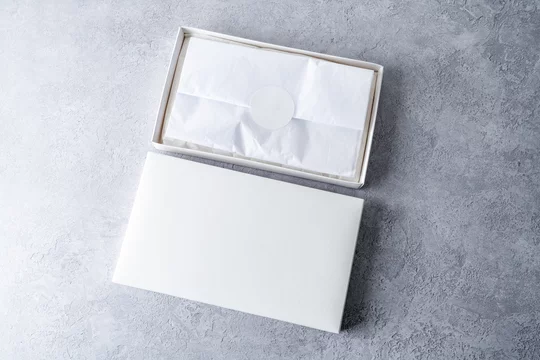 White square gift boxes with tissue wraping paper and round label, mockup on gray concrete background. From above, top view, minimalist concept