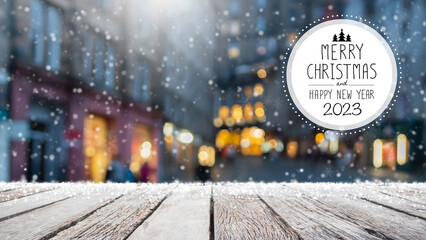 Christmas and Happy new year 2023 on empty wood table top on blur bokeh background with snowfall -...