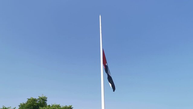 Low Angle View Of UAE Flag Flying At Half-mast Against Clear Sky. UAE Flag at half-mast blowing in the wind 