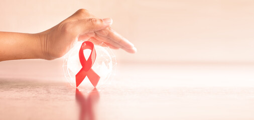 Hand covered 3d red ribbon on world map background, campaign for World AIDS Day on 1 December - 547604381