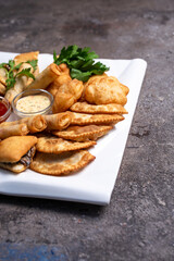 assorted Asian pastries on a white plate top view. baursaks, chebureks and bilyashi