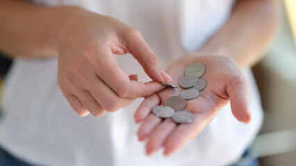 Closeup of woman counts coins in her hands.