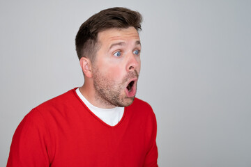 Shocked unshaven man expressing surprise on camera isolated over gray background