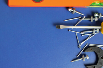 construction tools, repair equipment, screwdrivers, level, nails on a blue background, copy space