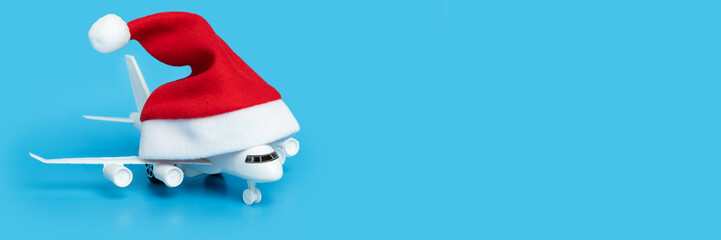 plane in a christmas santa hat on a blue background, holiday flight sale, airplane tickets, online...