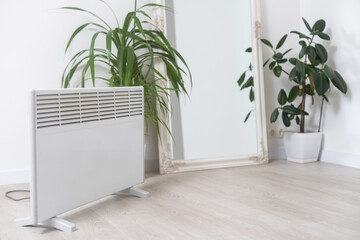 plant and electric heating battery on a gray background, harm dry air for houseplants concept, heating season