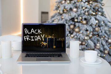 Black Friday shopping concept written in laptop's black screen against blurred christmas lights background