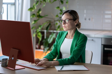 Businesswoman works on important project in cozy home office with green houseplants. Young...