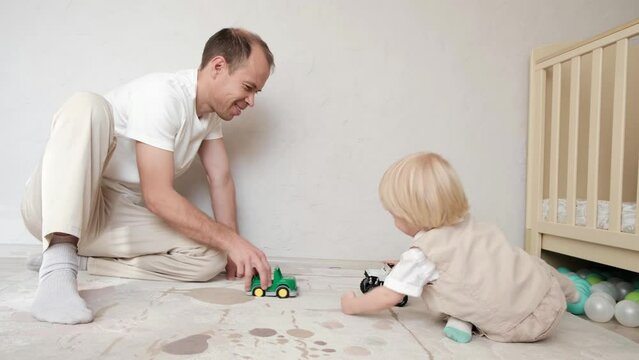 Father plays toys in the children's bedroom with his little son
