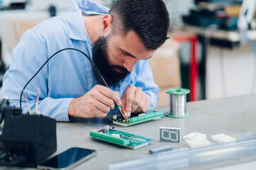 Electronics engineer working in a workshop with tin soldering parts