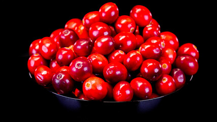 Cranberries on a black background. Ripe and organic red cranberries in a black bowl. Ingredient for Christmas and Thanksgiving dishes.
