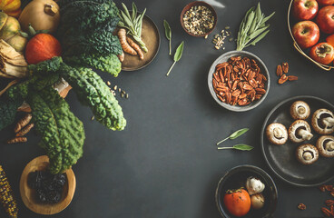 Seasonal food background with organic vegetables from garden in basket: kale, pumpkins,apples and other ingredients für autumn or winter cooking. Top view. Frame