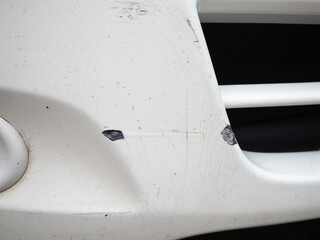 Scratches on white car at front bumper after accident.